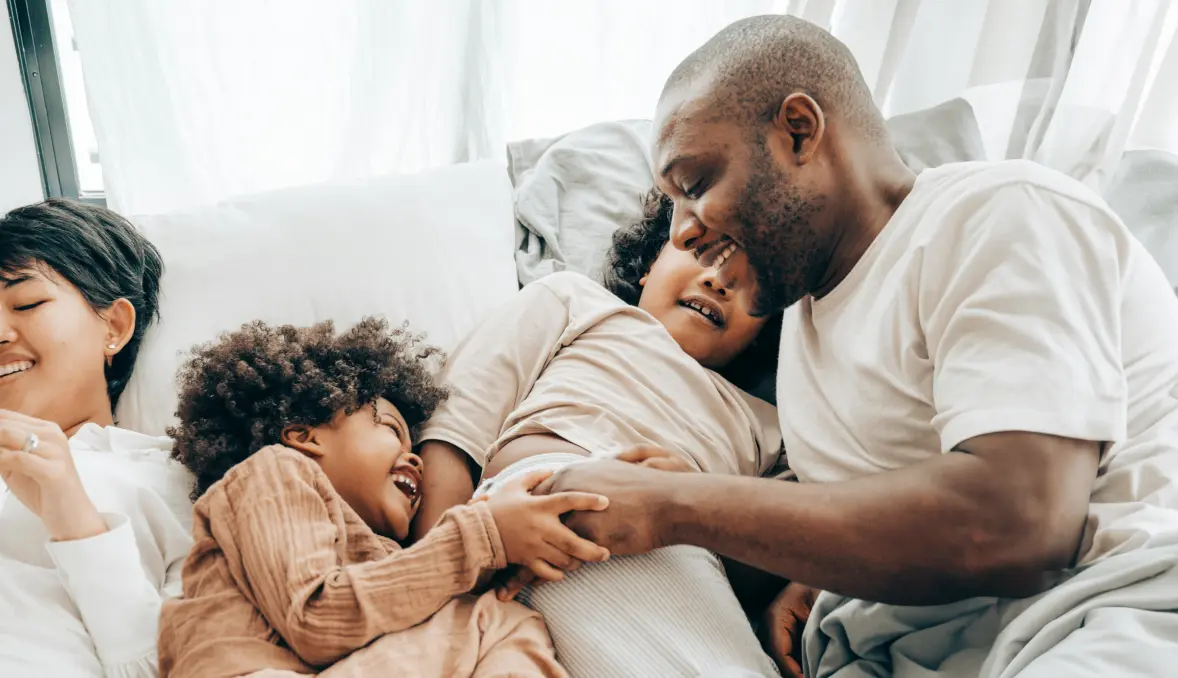 Family of four lying in bed laughing