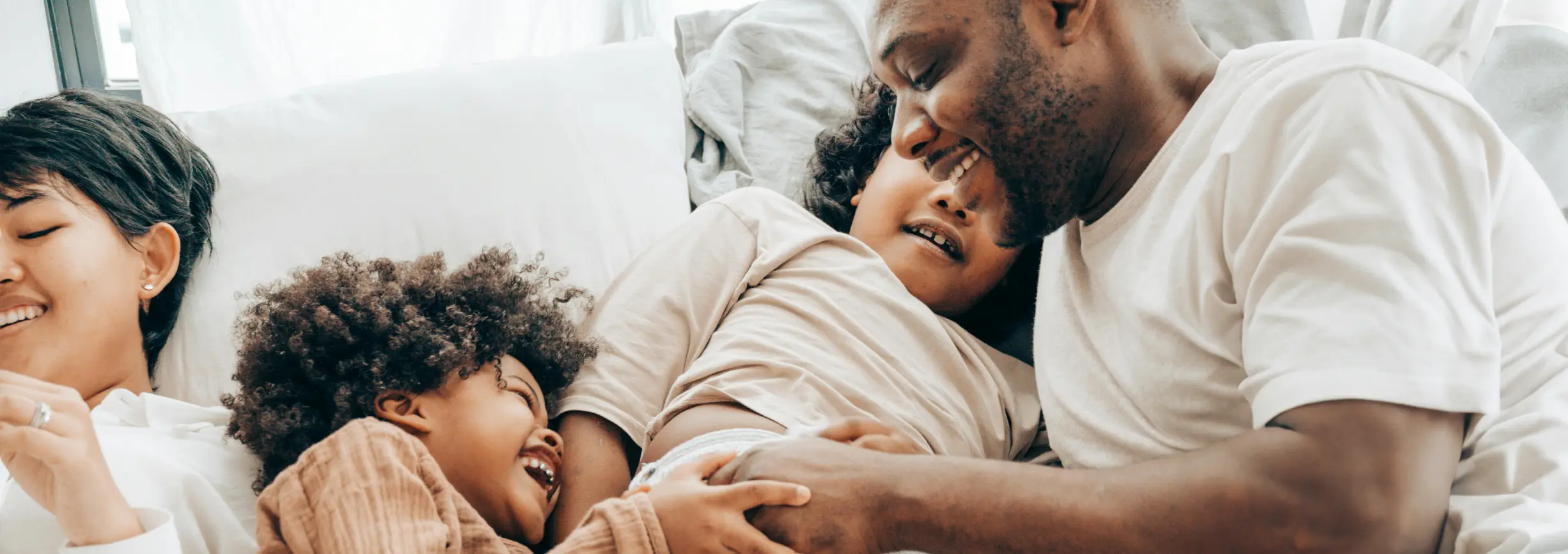 family of four lying together in a bed laughing